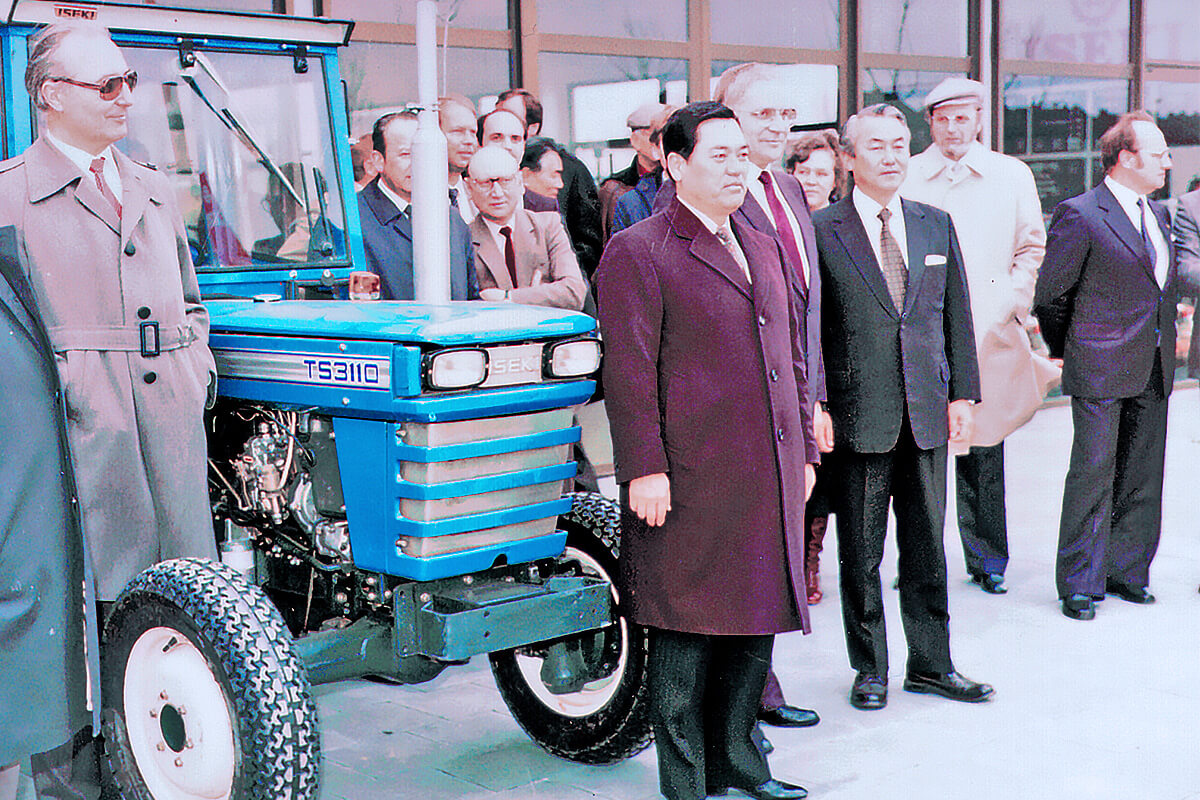 Japanische und deutsche ISEKI-Unternehmer stehen neben einem Traktor